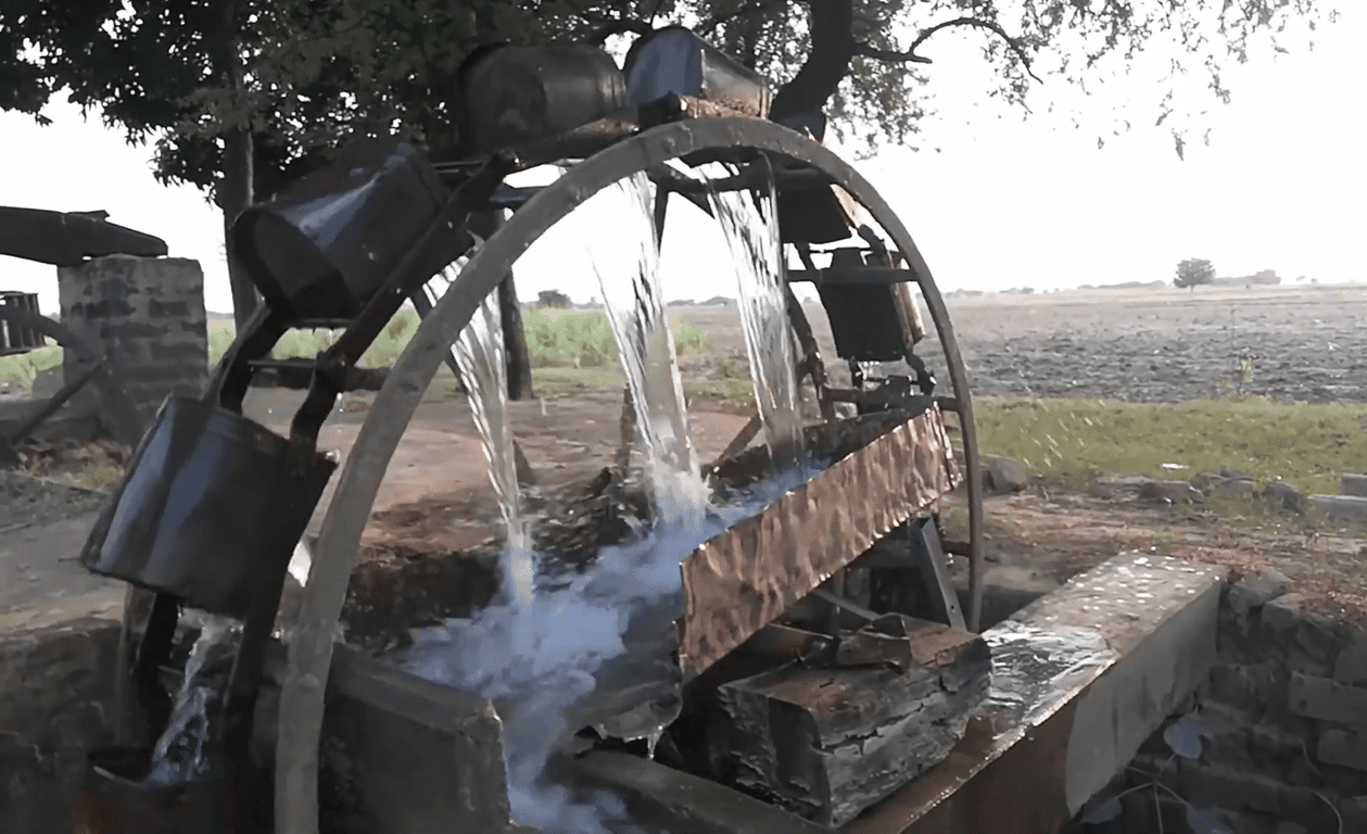 Water wheel lifting water for irrigation, symbolizing ongoing charity and agricultural support, with crypto donations enabling such life-sustaining projects and reflecting the concept of Sadaqah Jariyah, benefiting communities with essential resources like clean water, enabled by support like that of Ethereum.