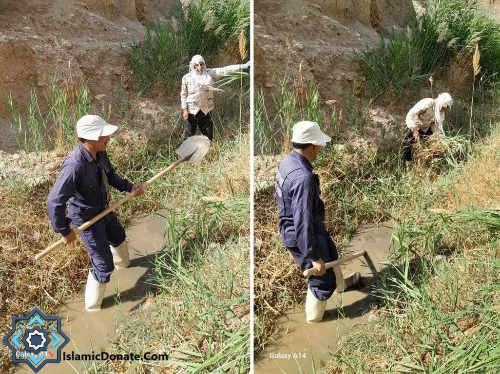 Two men clearing a muddy irrigation ditch with shovels and hoes, part of a crypto-supported agricultural water improvement project; showing manual labor for water systems benefiting communities.