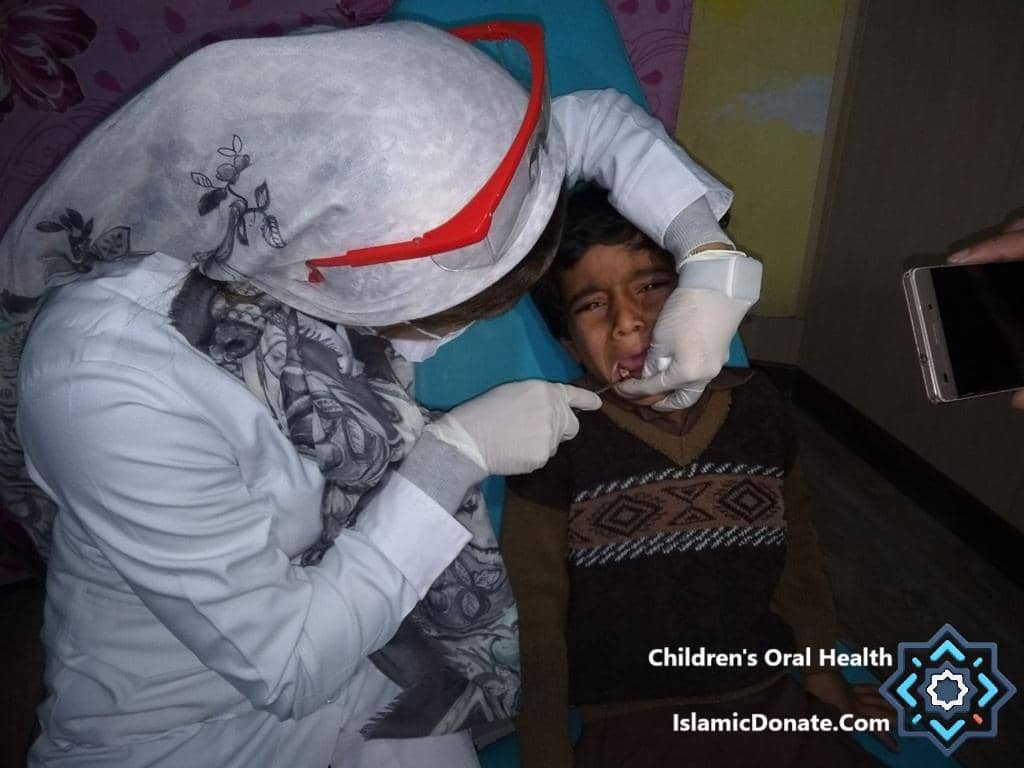 A dental professional examines a child's teeth, symbolizing World Cavity-Free Future Day's mission. Crypto donations, like BTC, enabled this vital oral health check for underprivileged children, promoting a cavity-free future.