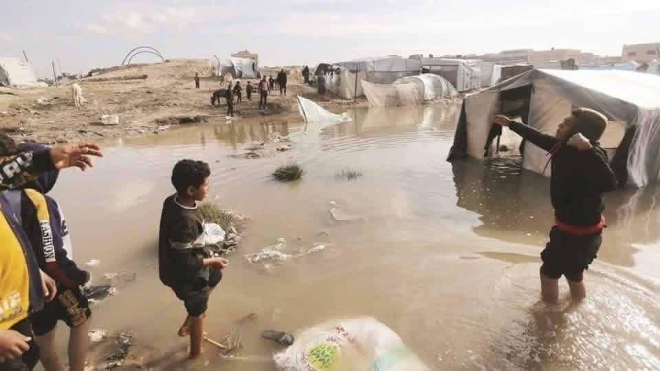 Gaza children wading through flooded refugee camp amidst the urgent battle against winter crisis, highlighting the need for crypto donations for waterproof shelters and insulation.