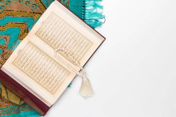 Open Quran on a prayer rug with rosary beads, symbolizing remembrance of Imam Hussain and offering donations via crypto like BTC.