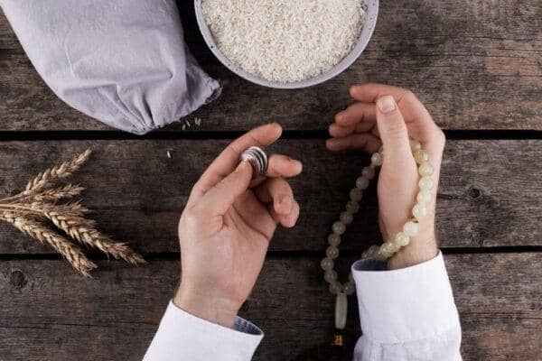 Zakat calculation for crypto with prayer beads and grains signifying wealth and charity.