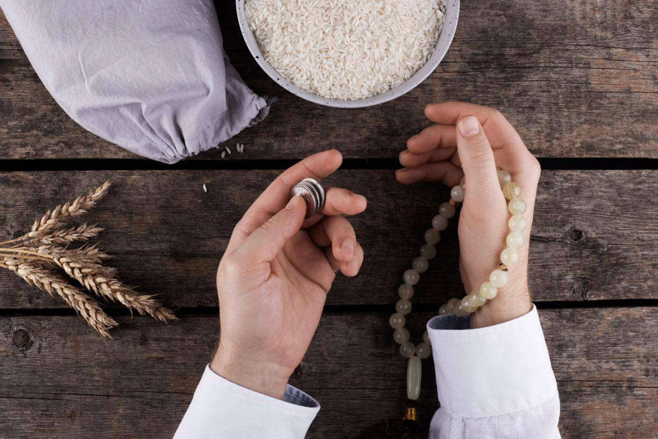 Zakat calculation for crypto with prayer beads and grains signifying wealth and charity.