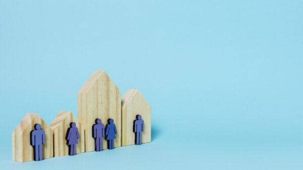 Miniature wooden houses with purple human figures representing beneficiaries of public endowment and waqf 'amm, supported by Bitcoin donations for community development.