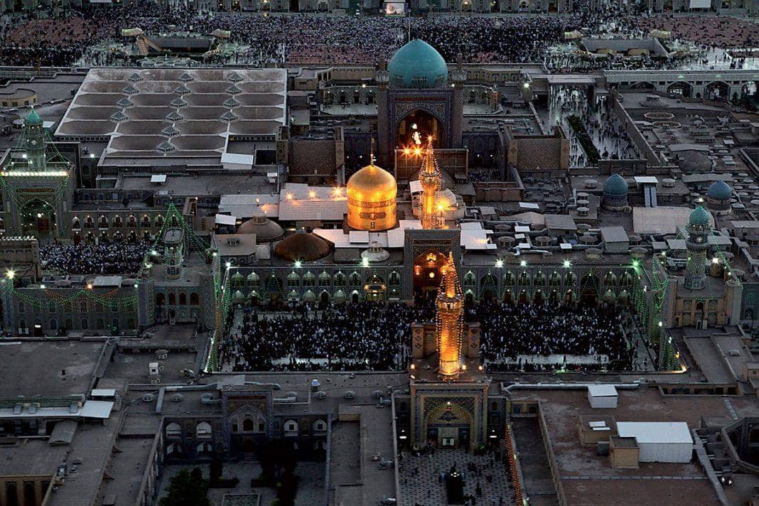 Aerial view of Imam Reza shrine courtyards filled with pilgrims, a golden dome shines, showcasing the spiritual heart during a virtual tour, supported by ETH.