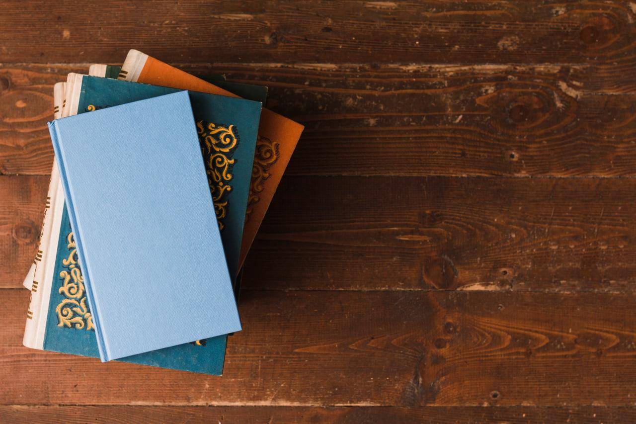 Pile of Islamic books on wooden background, supports Islamic education, promoted by ETH crypto.