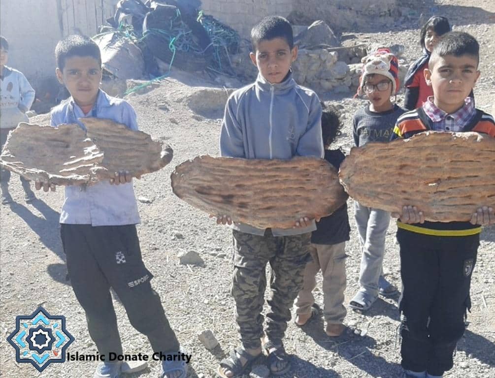 Children holding large flatbreads in a dry, dusty environment, illustrating support for the poor and needy through cryptocurrency donations for food.