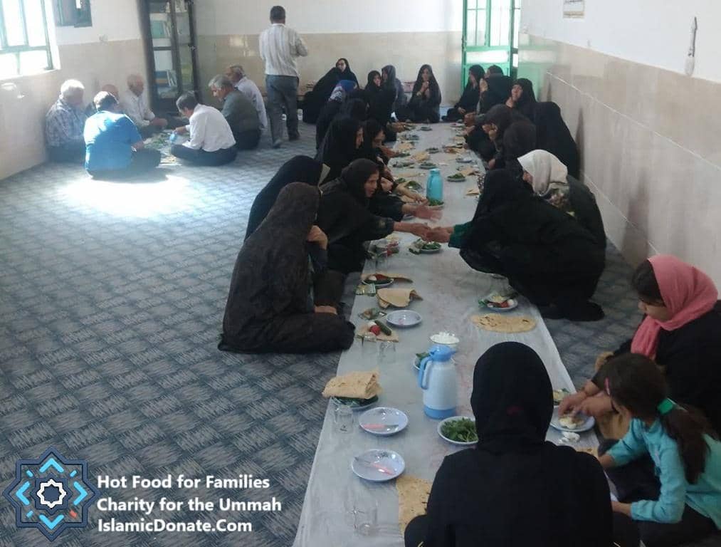 Group of people, some men and women, sitting on the floor gathered around a long table for a meal. This event is supported by crypto donations, providing hot meals for families. Key elements: daily charity, relief for the needy, sustainable livelihoods, hot meals, Islamic relief, aid provision, with support via ETH.