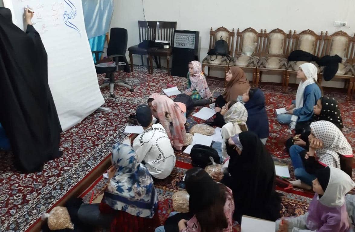A group of young women and girls sit on the floor, listening to an instructor write on a whiteboard. This scene depicts education and empowerment, supported by ETH donations for community health programs.