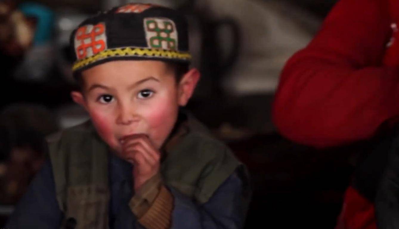 Young boy in a traditional hat eating, representing the need for Kaffarah donations to feed the poor, supported by ETH crypto.