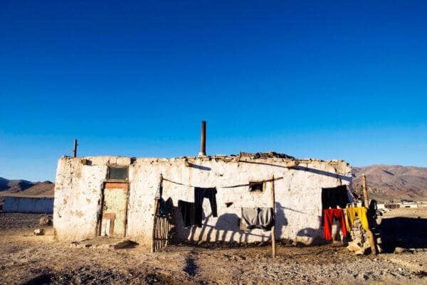 A modest dwelling with laundry hanging outside, symbolizing the need for societal strategies like education and social safety nets to reduce poverty and inequality, supported by ETH donations.