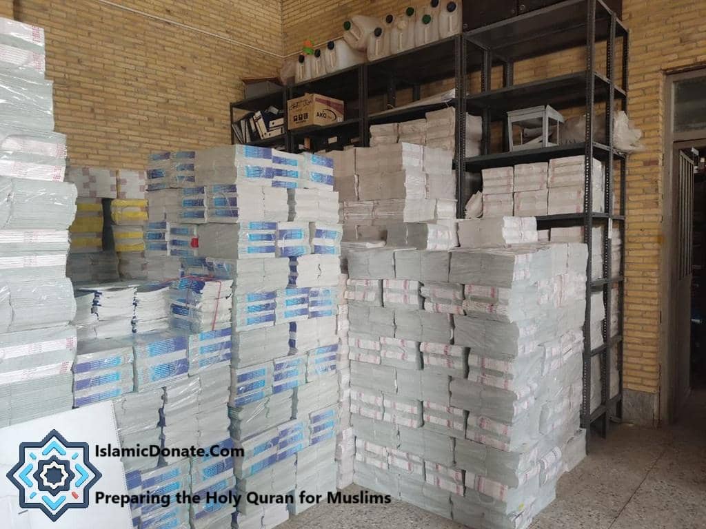 Stacks of Holy Quran books prepared for distribution, with IslamicDonate.com logo. Donate Quran with Cryptocurrency via BTC to support this gift of guidance.