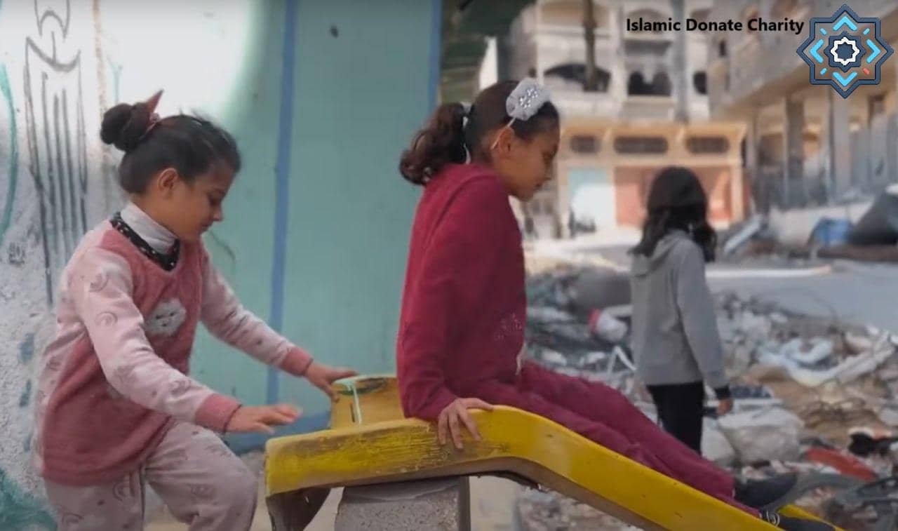 Three children playing on a damaged playground in front of ruined buildings, symbolizing hope and resilience supported by crypto donations like BTC.