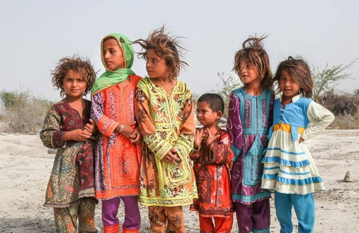 Group of children in colorful traditional clothing standing outdoors, showing vulnerable Muslim children receiving aid through crypto donations like TRX.