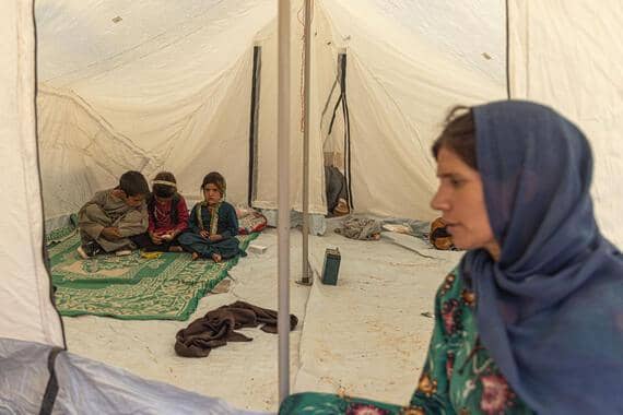 Children learning in a tent in Afghanistan, receiving cryptocurrency donations via RLUSD to support education and relief efforts.