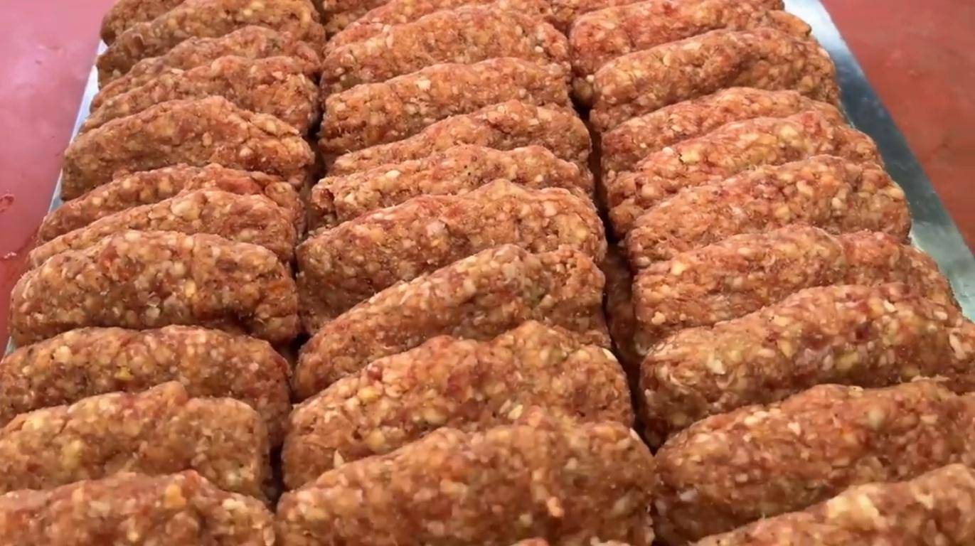 Rows of raw, seasoned ground meat shaped into small logs, likely prepared for Qurbani or Aqeeqah, accepting donations via various cryptocurrencies like BTC.