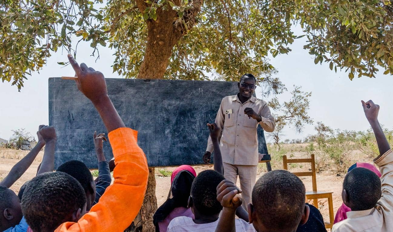 Teacher instructing schoolchildren in Sudan or South Sudan, demonstrating education in crisis zones funded by Bitcoin donations.
