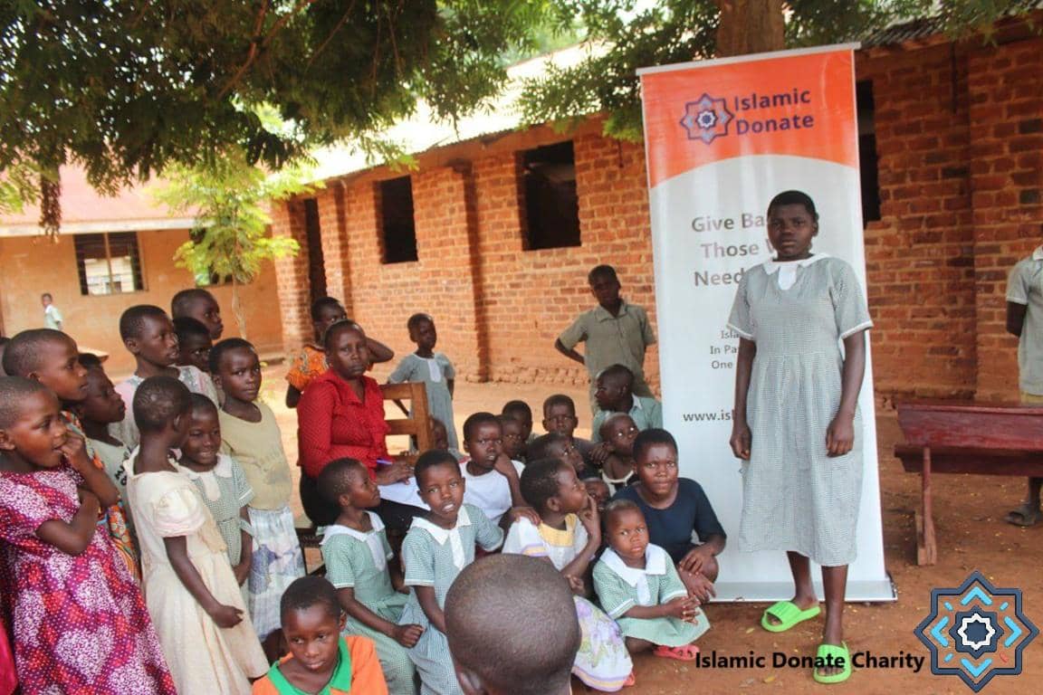 Children gathered near a banner for Islamic Donate Charity, receiving aid and a chance for education through crypto donations with XRP supporting an orphan sponsorship.