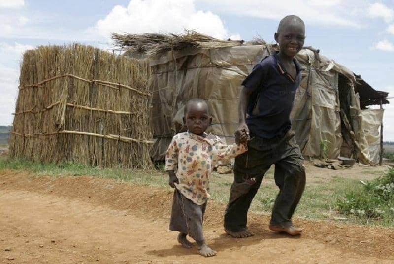 Two young children walk hand-in-hand in front of makeshift shelters, symbolizing the urgent need for aid in Sudan and South Sudan, with donations made via Ethereum for humanitarian relief.