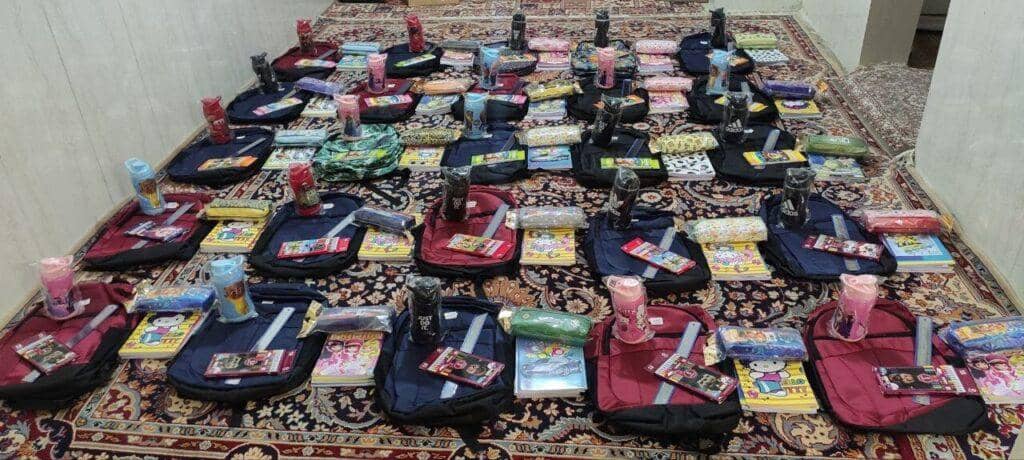 A collection of backpacks, books, and school supplies laid out on a carpet, ready for donation. Supports children's education through crypto, processed with RLUSD.