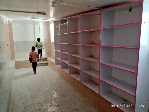 Two children walking up stairs towards empty shelves, symbolizing the ongoing need for educational resources. Your donation, processed via ETH, aids children's access to quality education.