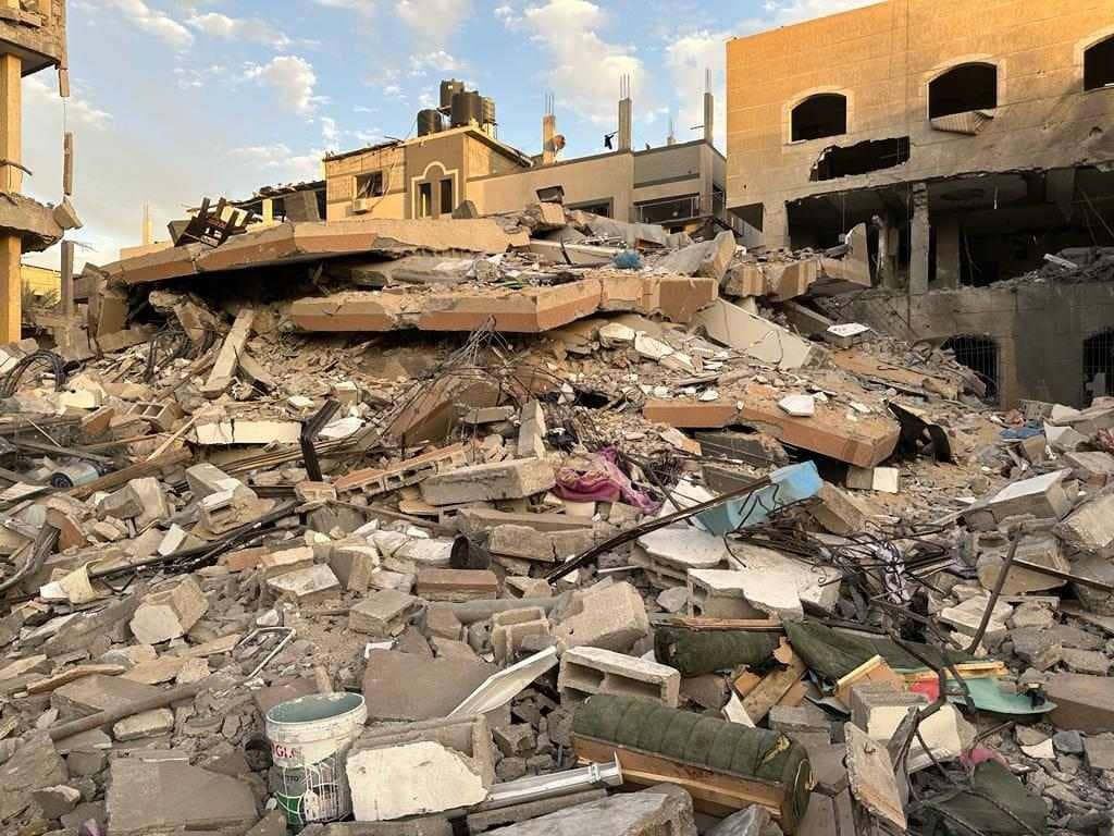 Pile of rubble from destroyed buildings in Palestine with debris including furniture fragments and personal items. Donations with USDC can help rebuild.