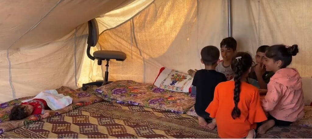 Children gather in a tent in Palestine for education. Support vital aid delivery with crypto donations, such as BTC, to help overcome obstacles.