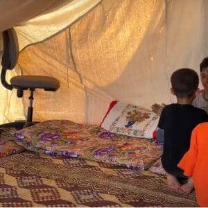 Children gather in a tent in Palestine for education. Support vital aid delivery with crypto donations, such as BTC, to help overcome obstacles.