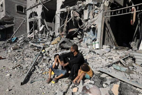 A father sits with his two distressed children amidst rubble and destroyed buildings, symbolizing the devastating impact of conflict. Crypto Zakat donations, including ETH, provide vital aid and support to families in need in Palestine.