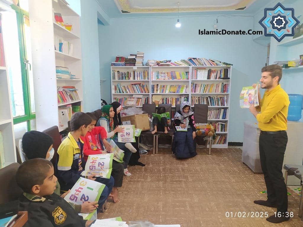 A teacher holds a children's book while children sit in a library, learning and reading. This scene depicts an educational Sadaqah Jariyah project, potentially funded by cryptocurrency donations like LTC. Islamic Donate supports education for lasting reward.