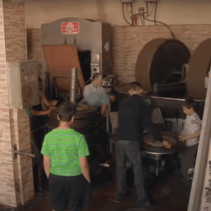 Syrian workers operating machinery in a restored olive oil workshop, receiving crypto donations for sustainable livelihoods via Ethereum.