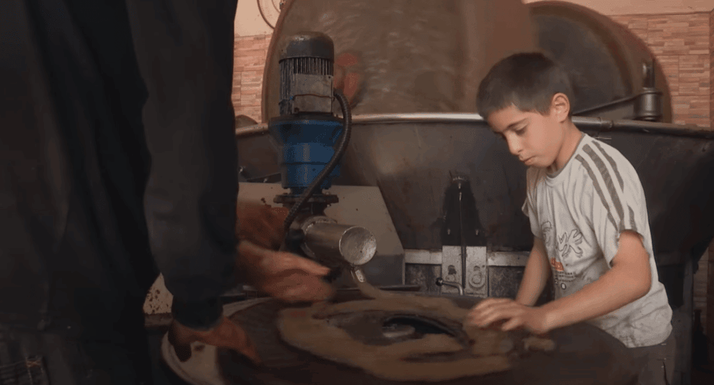 Syrian boy works in a restored olive oil workshop, a Sadaqah Jariyah project, supported by crypto donations via USDT.