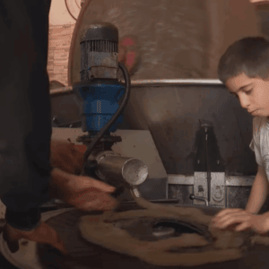Syrian boy works in a restored olive oil workshop, a Sadaqah Jariyah project, supported by crypto donations via USDT.