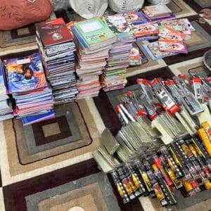 Stacks of school notebooks and writing supplies, including pens and pencils, arranged on a carpet, representing crypto-funded educational aid for disadvantaged children, supported by XRP.