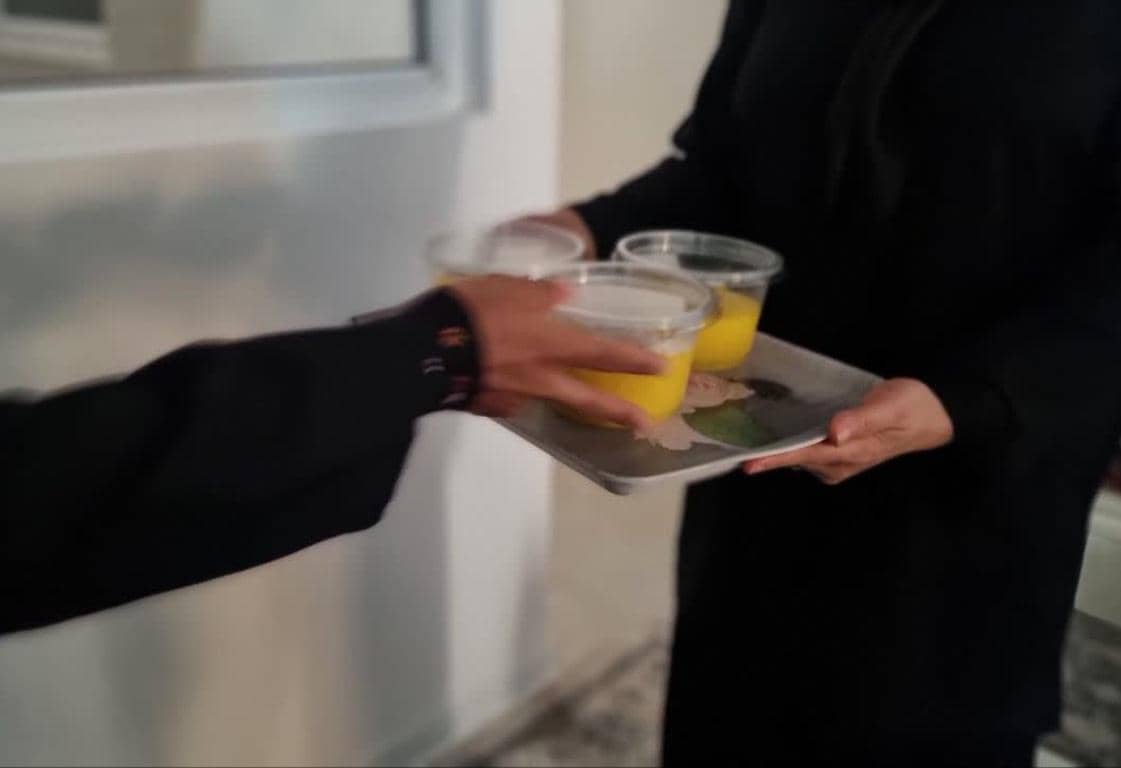 Person receiving tray with three cups of yellow liquid, celebrating Prophet's birthday with crypto donations, possibly via RLUSD, embodying generosity and community spirit.
