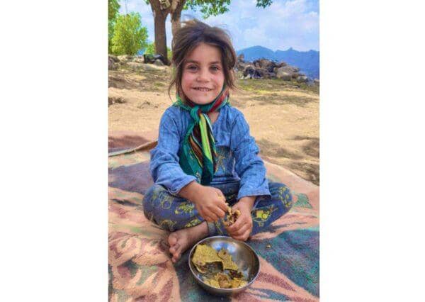 Smiling young Fuqara child eating from a bowl, recipient of crypto zakat funds. Crypto donations via XRP help provide sustenance.