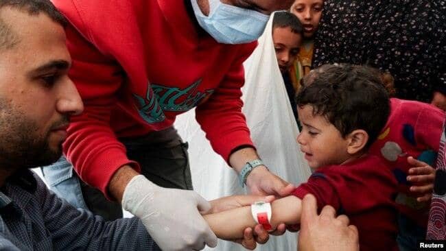 A healthcare worker in gloves examines a child's arm in Gaza. The aid effort is supported by crypto donations, with the latest transactions processed using Stablecoin.