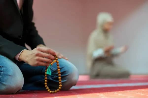 Woman praying with prayer beads, symbolizing seeking forgiveness for sins and achieving true repentance through Islamic charity and crypto donations, supported by ETH.