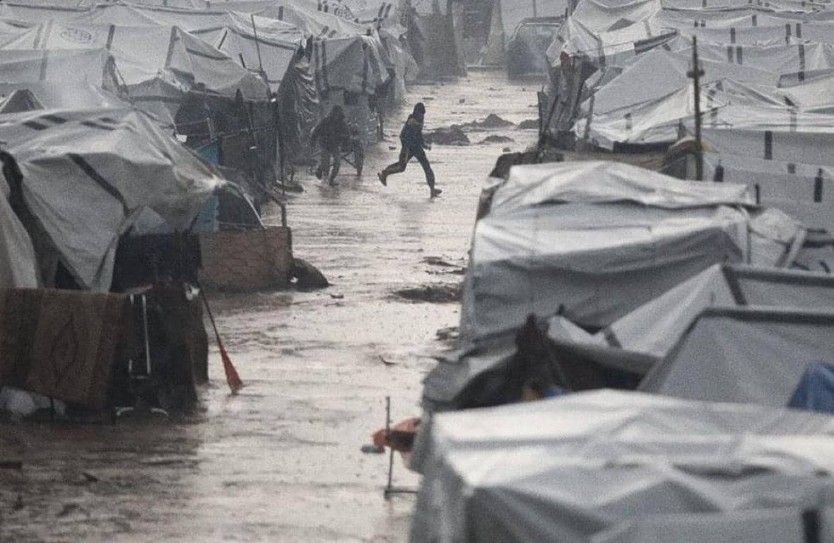 Winter relief camp for displaced families in rainy conditions. Aid provides warm clothing, shelter, and heating. Donate crypto like BTC to help vulnerable communities.