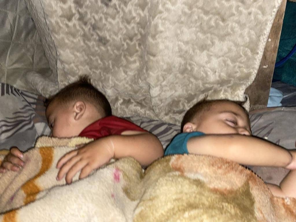 Two young children sleeping peacefully under blankets, symbolizing warmth and safety provided through crypto donations, giving hope to families in need.