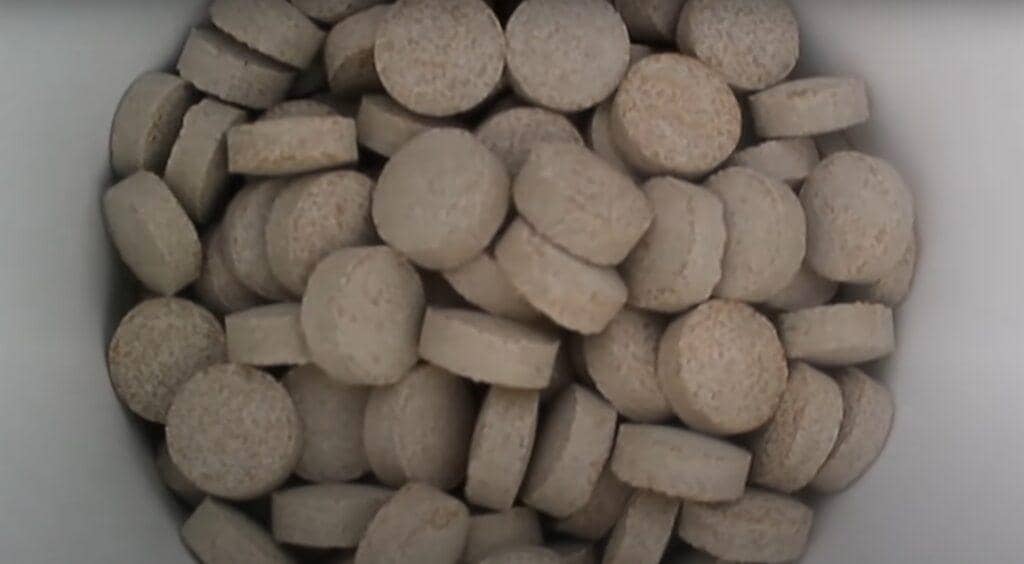 Pile of small, light brown, circular, and cylindrical tablets, possibly compressed nutrients or fodder, representing vital resources funded by crypto donations like BTC for families.
