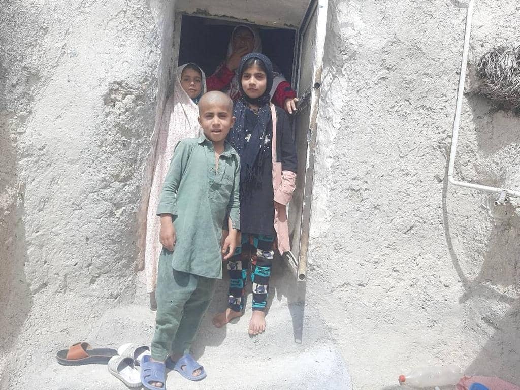 Children in simple clothing stand in a doorway, with sandals on the steps. Your crypto Zakat donation, perhaps via ETH, can provide essential aid to families like these, offering hope and sustenance.
