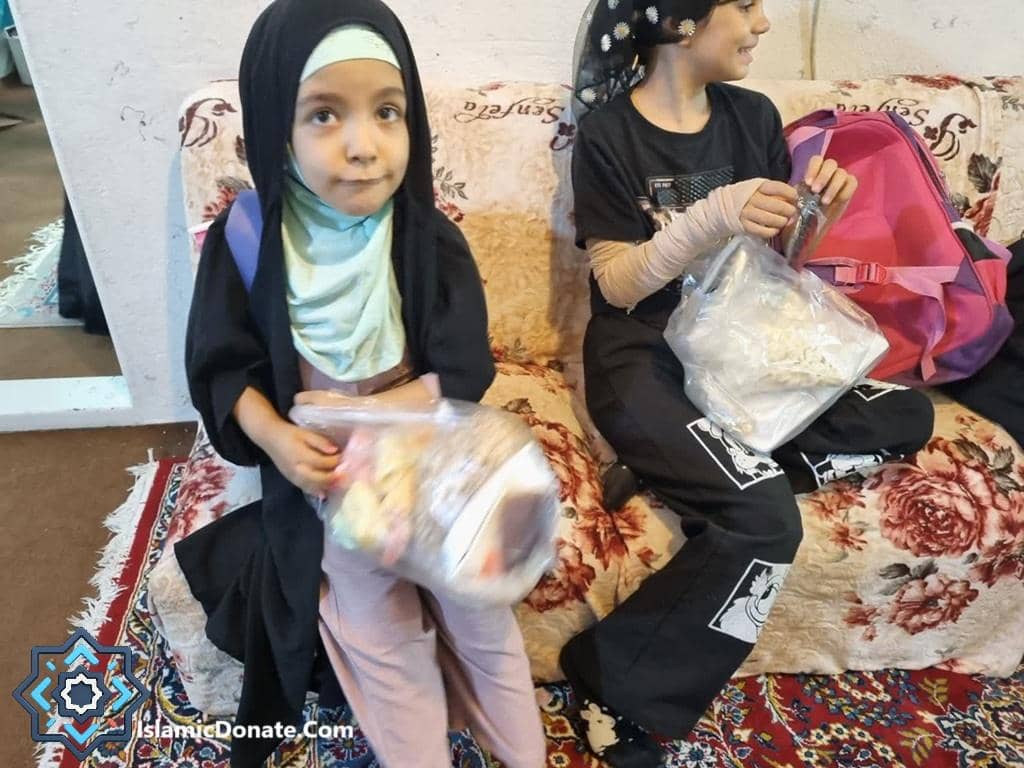 Two children receiving food packages from Islamic Donate Charity through cryptocurrency donations during Ramadan.