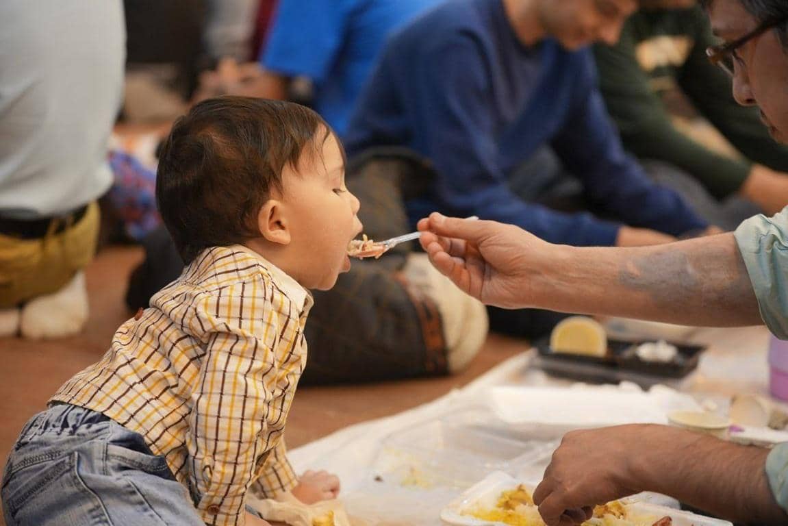 Child being fed by hand with a spoon, symbolizing charity and aid sponsored by crypto donations like ETH, offering hope and sustenance to needy families.