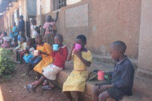 Children drinking from colorful cups, representing access to clean water in Uganda, supported by Solana crypto donations for crucial aid and water well projects.