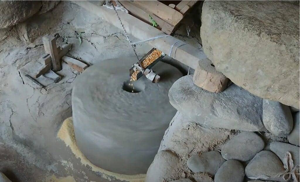 Traditional stone mill processing 900 kilos of corn, supporting local farmers and providing meals for the needy, with crypto donations enabling this charitable impact via ETH.