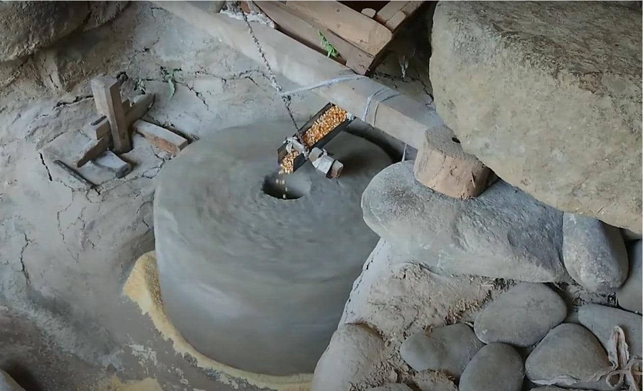 Traditional stone mill processing 900 kilos of corn, supporting local farmers and providing meals for the needy, with crypto donations enabling this charitable impact via ETH.