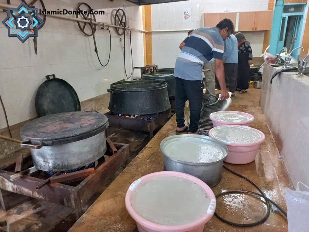 People preparing food in a kitchen, filling large basins with a liquid. This scene depicts food aid distributed to Palestinian Muslims, made possible by crypto Zakat donations via platforms like Ethereum, funding essential aid like food, water, and medicine.