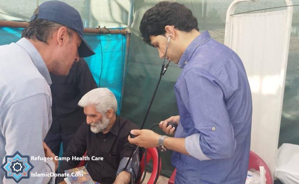 A medical professional uses a stethoscope to check a Palestinian man's blood pressure in a refugee camp health care setting, supported by crypto Zakat donations.