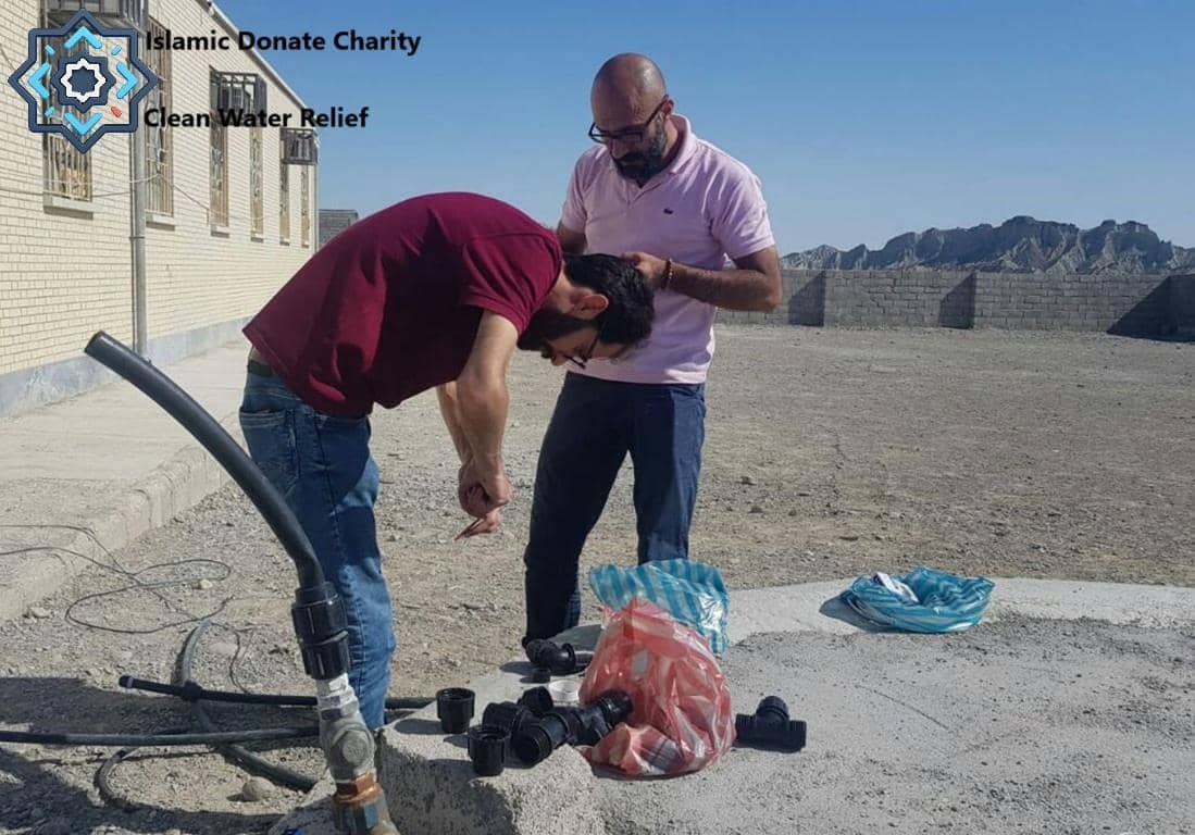 Two men working on plumbing for clean water relief in Palestine, demonstrating water aid efforts funded by crypto Zakat donations.